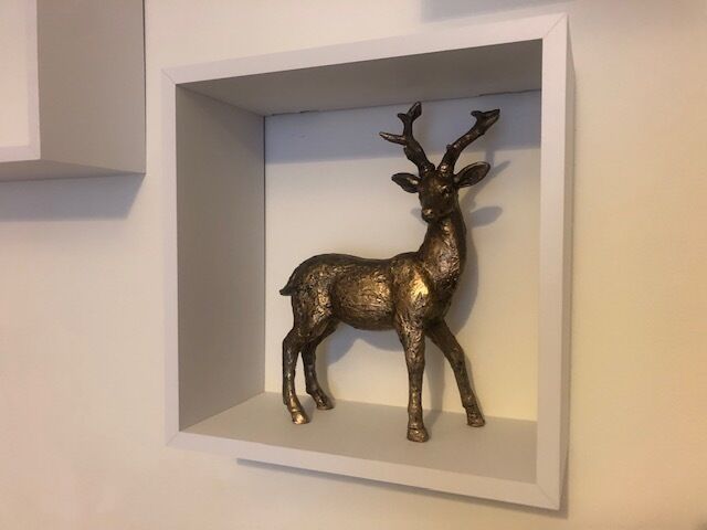 A framed deer sculpture on a wall.