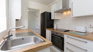 Una cocina moderna con un lavamanos de acero inoxidable, un refrigerador negro, un horno empotrado y una tostadora sobre la encimera.