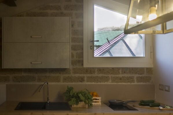 Una cocina con ventana, lavamanos y encimera de madera.