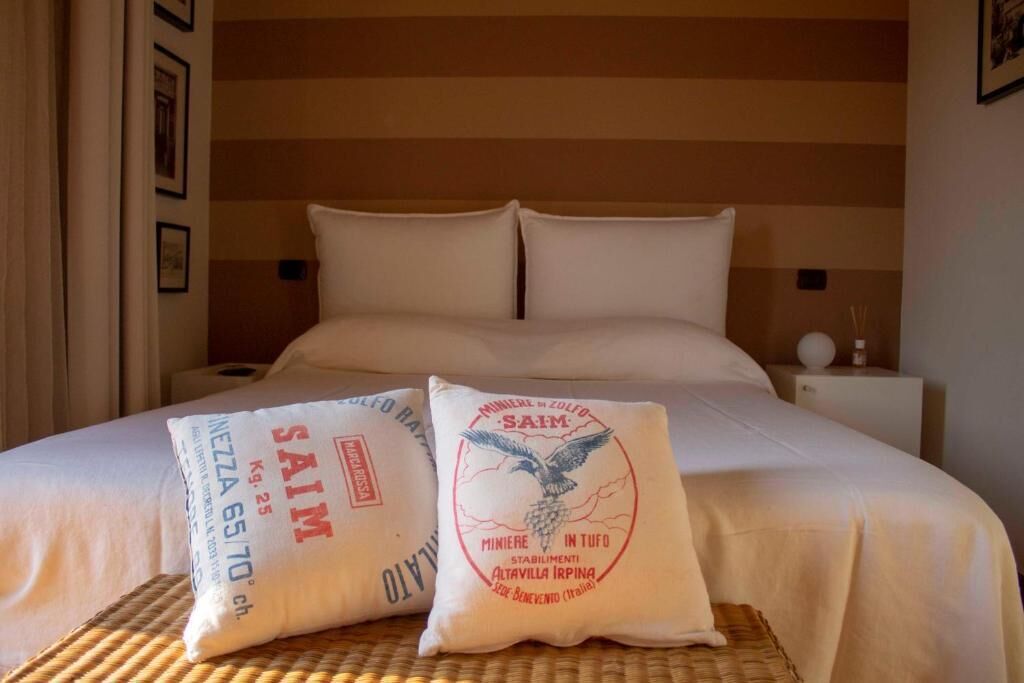 Une chambre d’hôtel avec un lit, deux oreillers et une table de chevet avec une lampe.