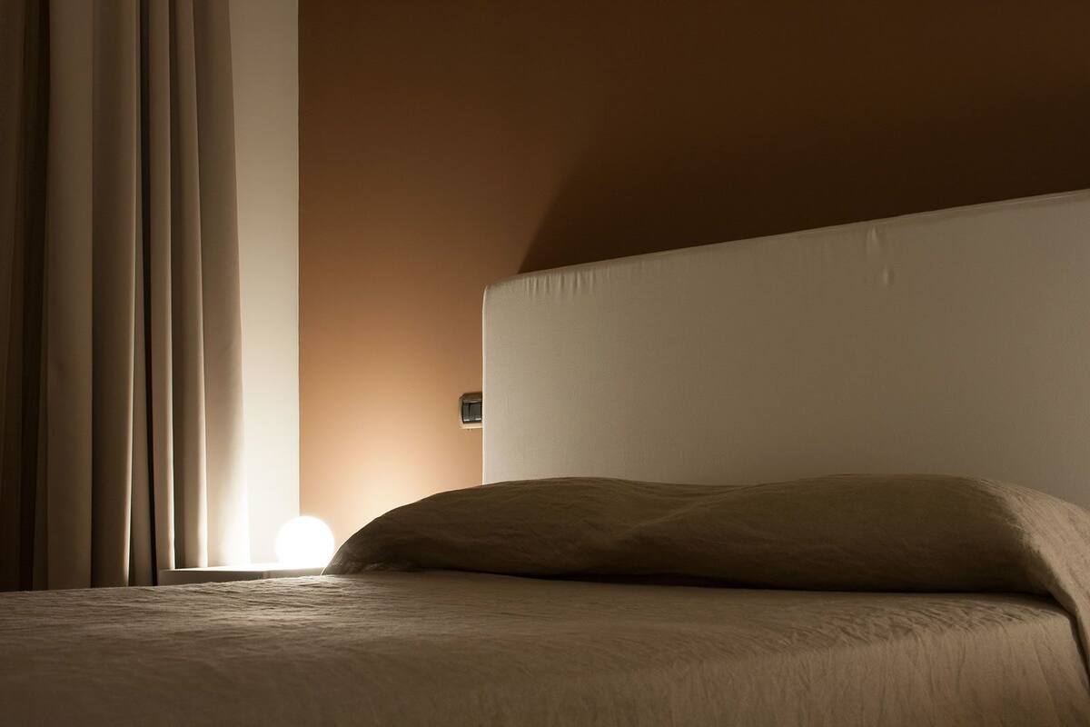 Een slaapkamer met een bed, gordijnen en een wandlamp.
