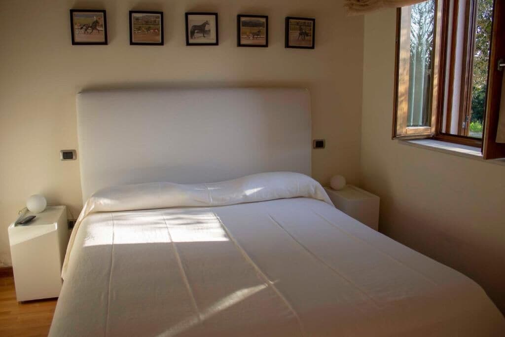 Una camera da letto con un letto grande, un comodino, una scrivania e una finestra vista alberi.