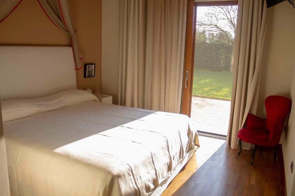 Une chambre à coucher avec un lit, une chaise et une porte donnant sur un jardin.