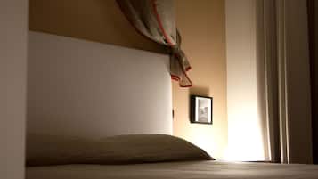 Un dormitorio con cama, un cuadro en la pared y una ventana con cortinas.