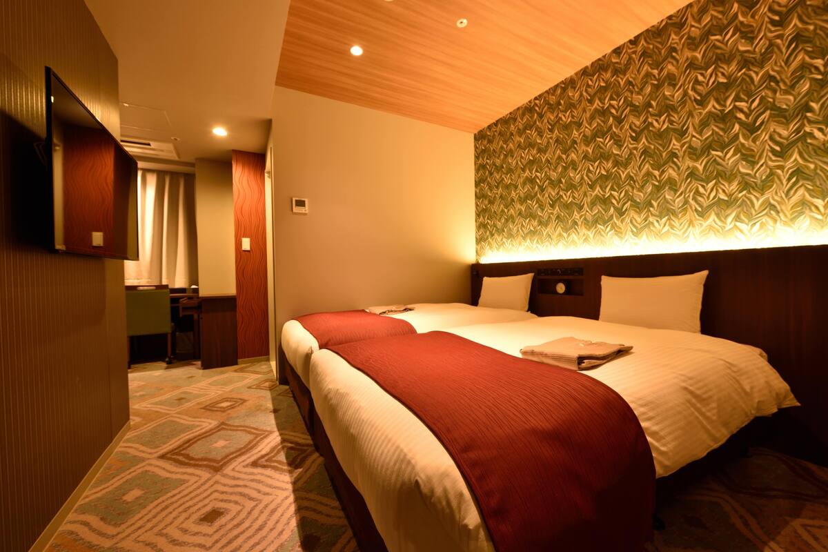 A hotel room with a large bed, a desk, and a mirror.
