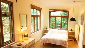 A bedroom with a large bed, wooden dresser, and multiple windows providing natural light. - Ferienwohnung Schuster (Garlstorf am Walde)