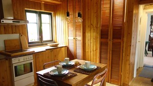 A wooden interior with a kitchen area, including a stove, oven, and dining table set with plates, cups, and a bowl. - Ferienwohnung Schuster (Garlstorf am Walde)