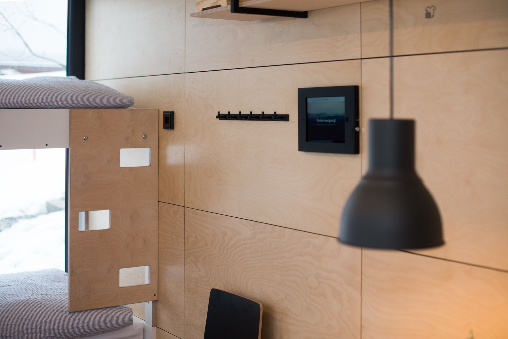 A modern room with a wooden wall, a black pendant light, and a small black-framed picture.