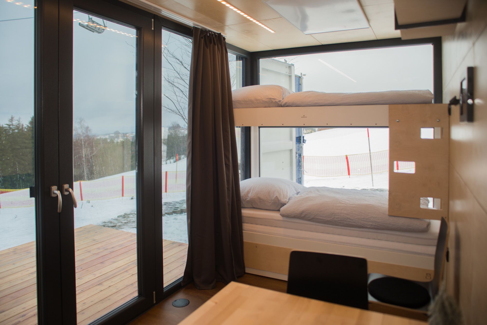 A cabin with a bunk bed, a wooden deck, and a sliding glass door.