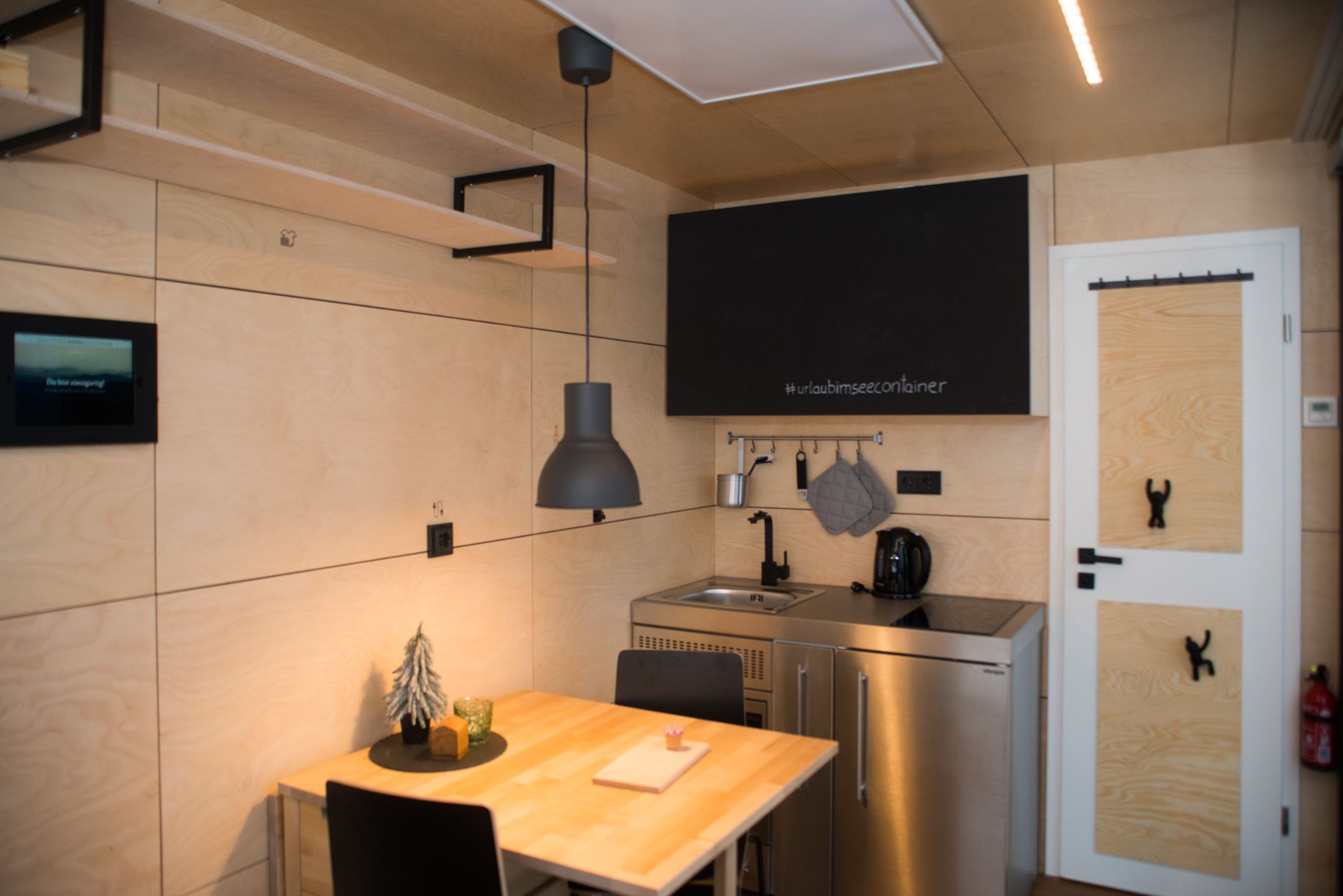 A compact kitchen with a built-in oven, a sink, and a small dining area with a table and chairs.