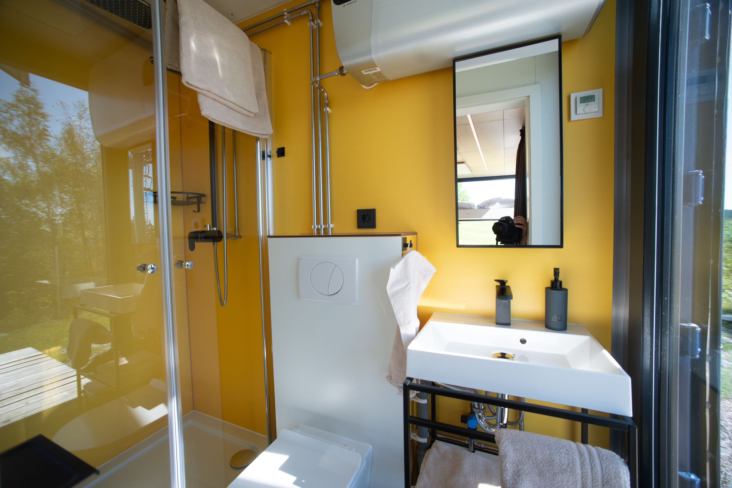 A bathroom with a glass shower enclosure, a white sink, and a mirror above it.