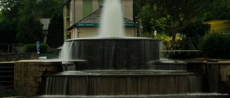 Una fuente con chorros de agua frente a un edificio de fachada verde y beige.