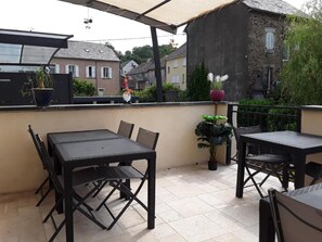 An outdoor patio with two tables and chairs, surrounded by potted plants and a view of residential buildings. - L' Amarante chambres d'hôtes (Villefranche-de-Panat)
