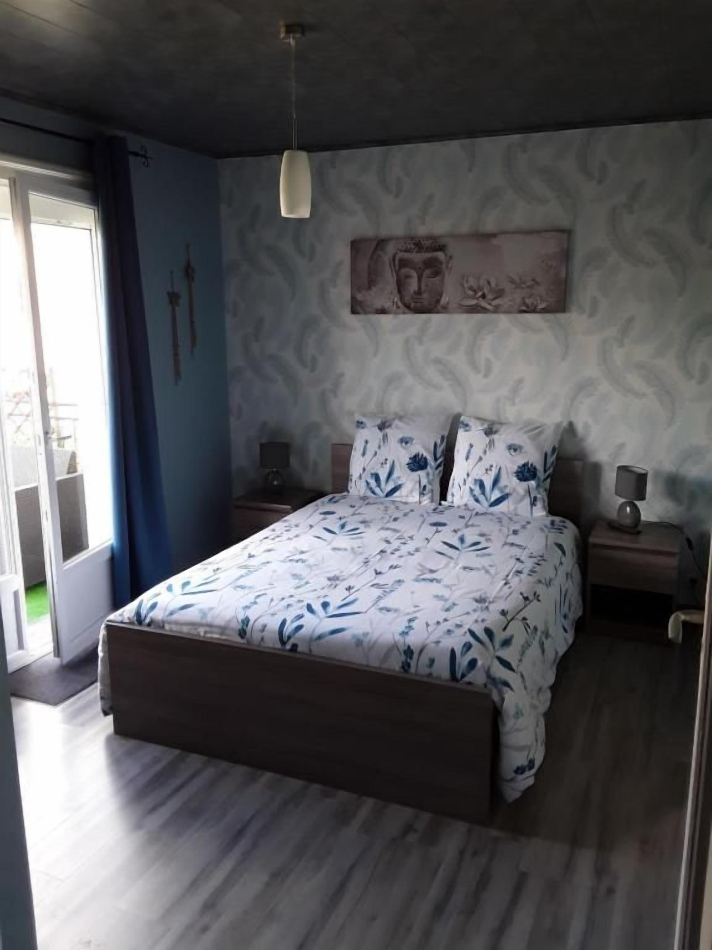 A bedroom with a bed, bedside tables, a hanging light fixture, and a wall-mounted artwork.