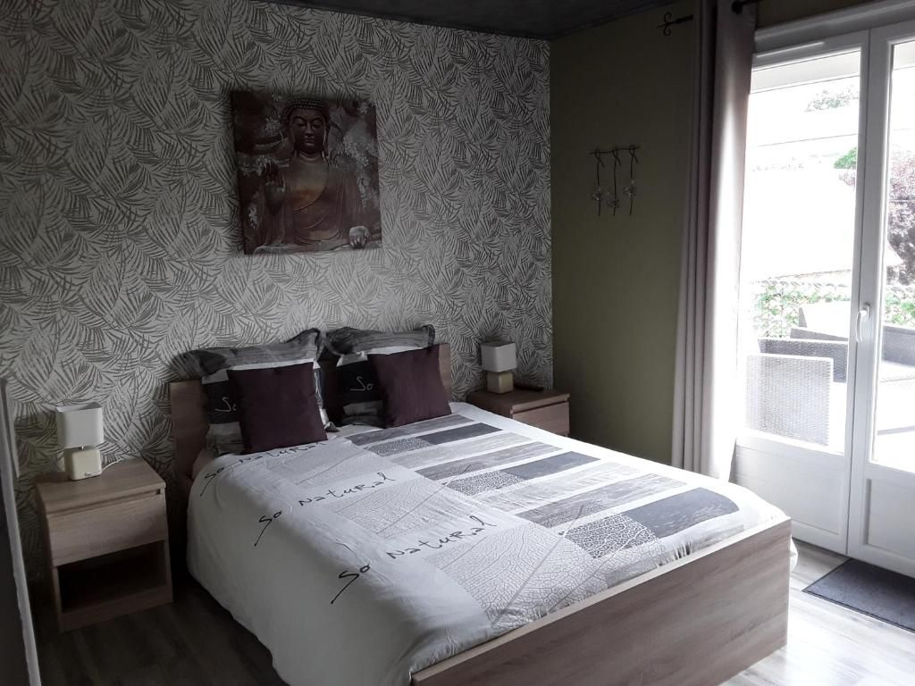 A bedroom with a bed, a nightstand, a wall-mounted artwork, and a view through a door.