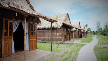 Una hilera de casas de campo con techos de paja, puertas y ventanas de madera, conectadas por un camino pavimentado.