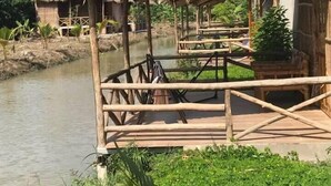 Una estructura de madera rústica con techo de paja, ubicada a la orilla de un río tranquilo.