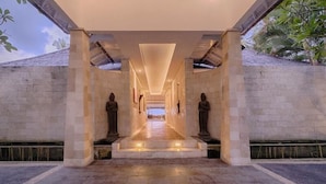 A corridor with a stone floor and two large statues on either side, leading to a distant view. - Kutus Kutus Saba Beach Villa (Blahbatuh)