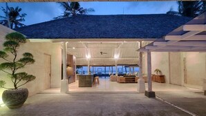 A modern, open-plan living area with a view of the ocean, featuring a large seating area and a dining space. - Kutus Kutus Saba Beach Villa (Blahbatuh)