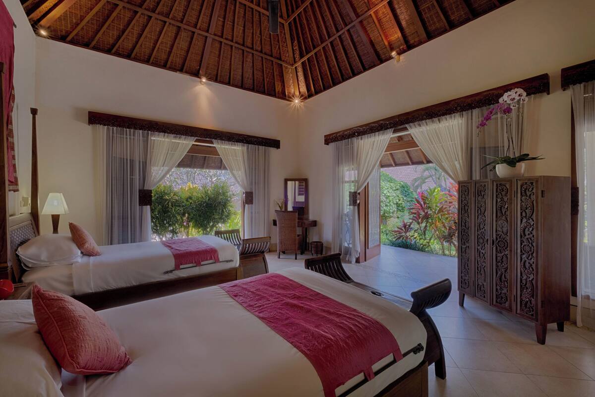 Une chambre d’hôtel avec deux lits, un coin repas et une vue sur la verdure.