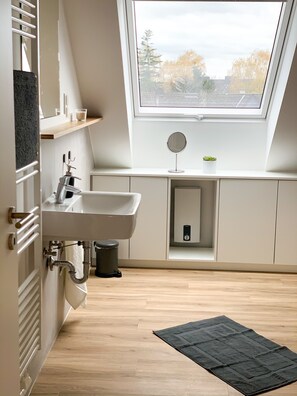 A modern, compact bathroom with a skylight, a sink, and a mirror. - Glück Auf Appartements Rembrandtstraße (Essen)