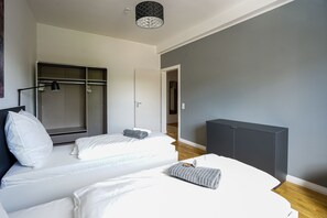 A modern bedroom with a bed, a walk-in closet, a radiator, and a grey wall. - Glück Auf Appartements Rembrandtstraße (Essen)