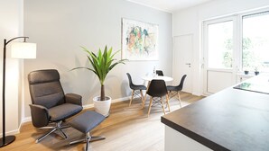 A modern living room with a grey sofa, a small table, and a potted plant. - Glück Auf Appartements Rembrandtstraße (Essen)