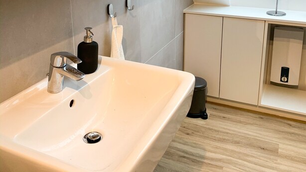 A modern bathroom with a skylight, a large sink, and a mirror. - Glück Auf Appartements Rembrandtstraße (Essen)