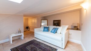 A spacious living room with a white sofa, a small white side table, a patterned rug, and a skylight. - Boutique - Lodge & Suites (Crotone)
