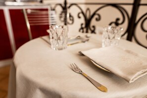A table set with a white tablecloth, a folded napkin, a fork, a knife, and two clear glasses.