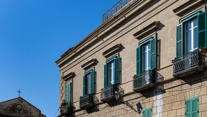 A building with multiple windows, green shutters, and balconies with wrought iron railings. - Boutique - Lodge & Suites (Crotone)