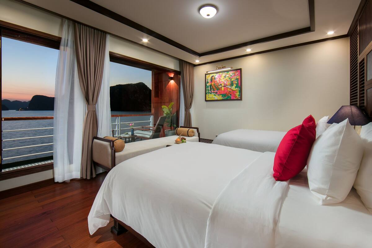 Quarto de hotel com uma cama grande, vista para a água e um quadro na parede.