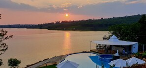 Un cadre paisible au bord d’un lac, avec une piscine, un belvédère et un espace repas offrant une vue sur l’eau.