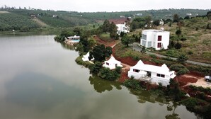 A lakeside property with white buildings, a swimming pool, and a view of the surrounding greenery. - Ho Gia Trang (Tan Ha Lam Ha)
