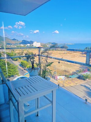 A balcony with a view of a coastal area, a road, and some greenery. - Sunrise Ninh Thuan Hotel (Ninh Chu)