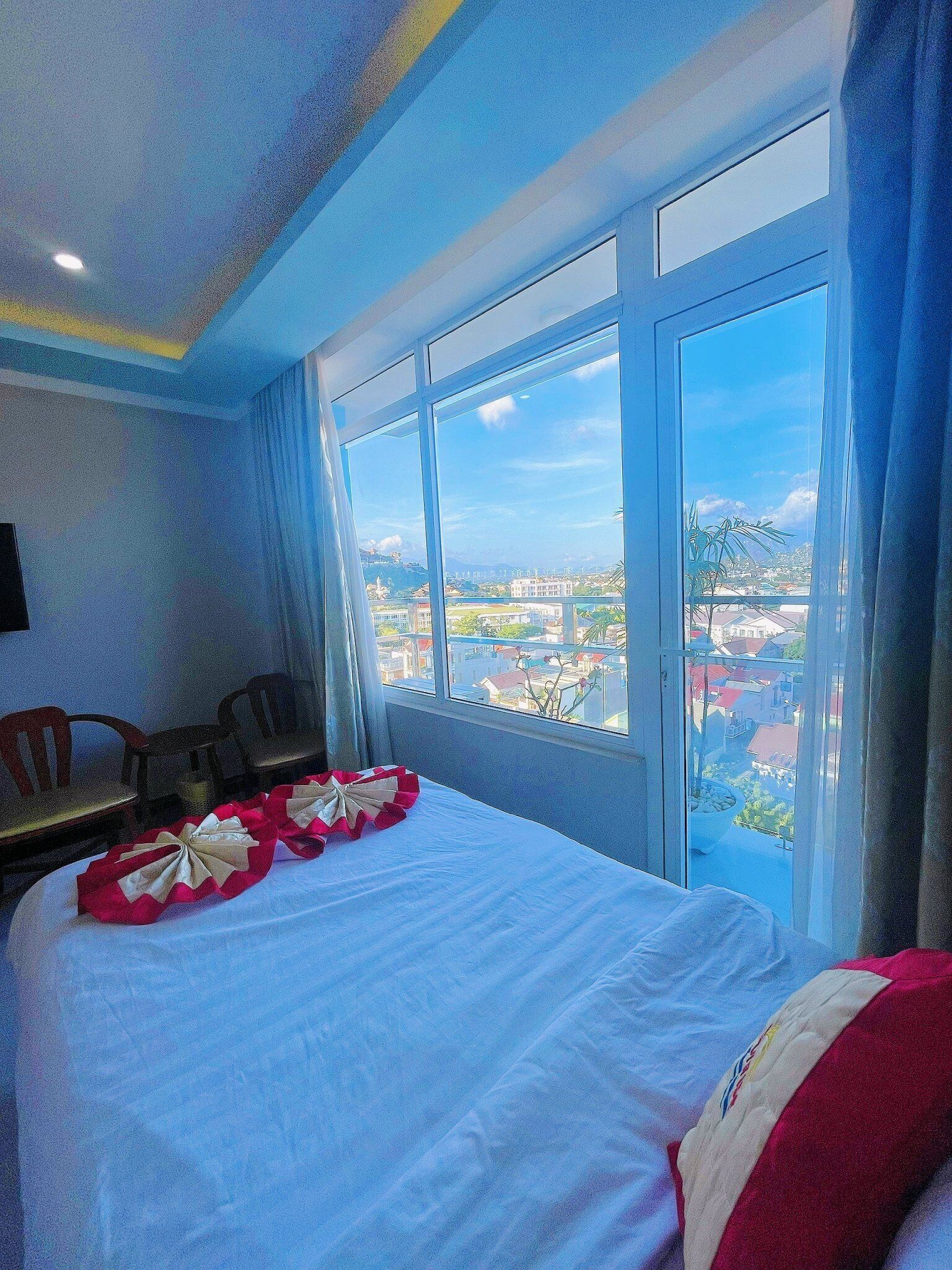 Una habitación de hotel con una cama grande, vistas a la ciudad y un comedor con sillas.