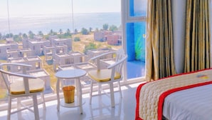 Habitación de hotel con balcón, cama y vistas al mar y edificios.