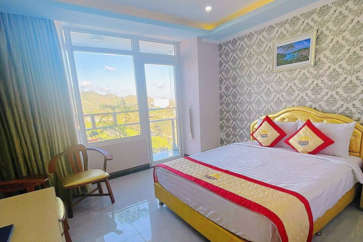 A hotel room with a large bed, a desk, and a view of the outdoors.