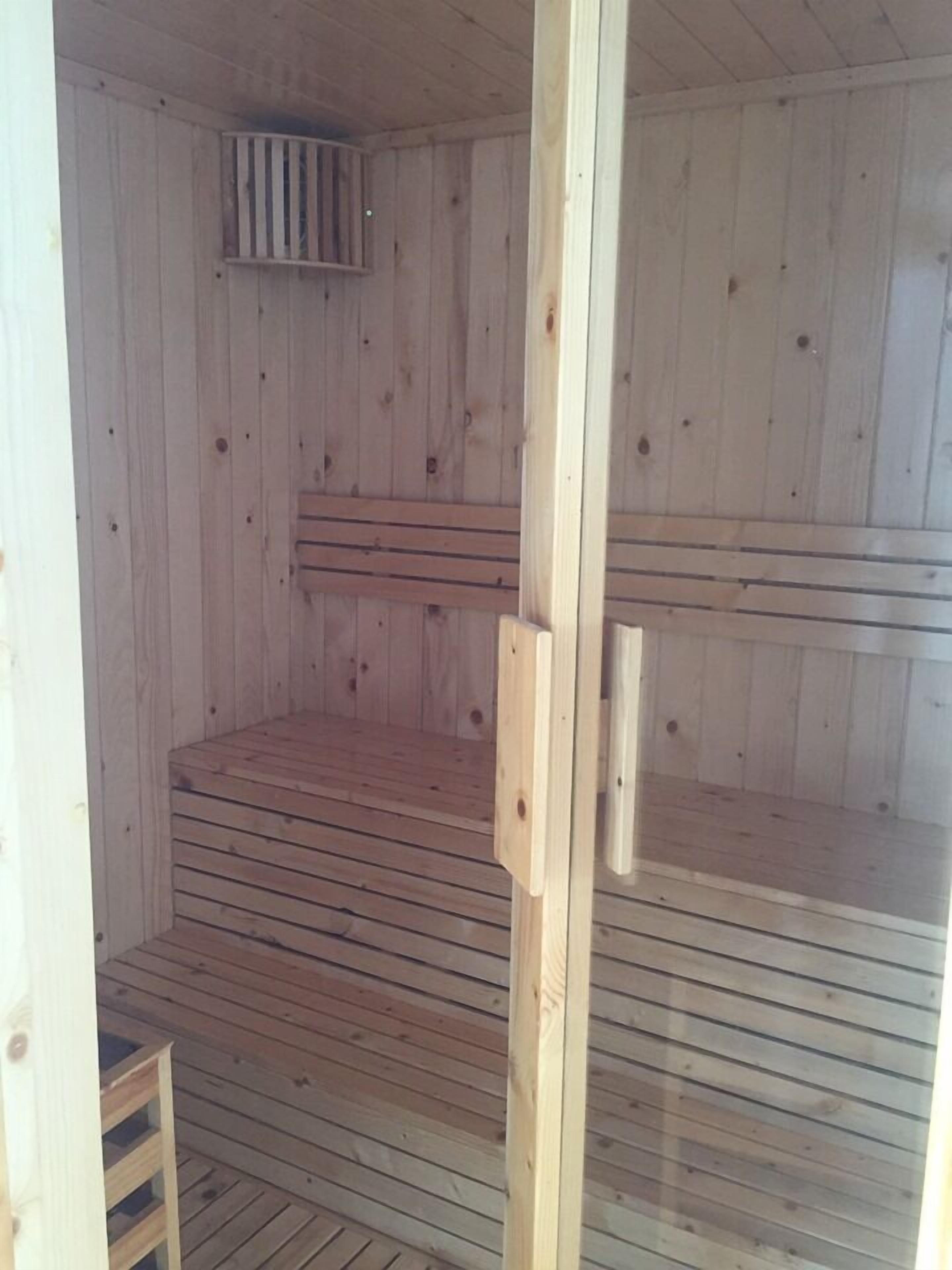 Una sauna in legno con una panchina e una piccola finestra.