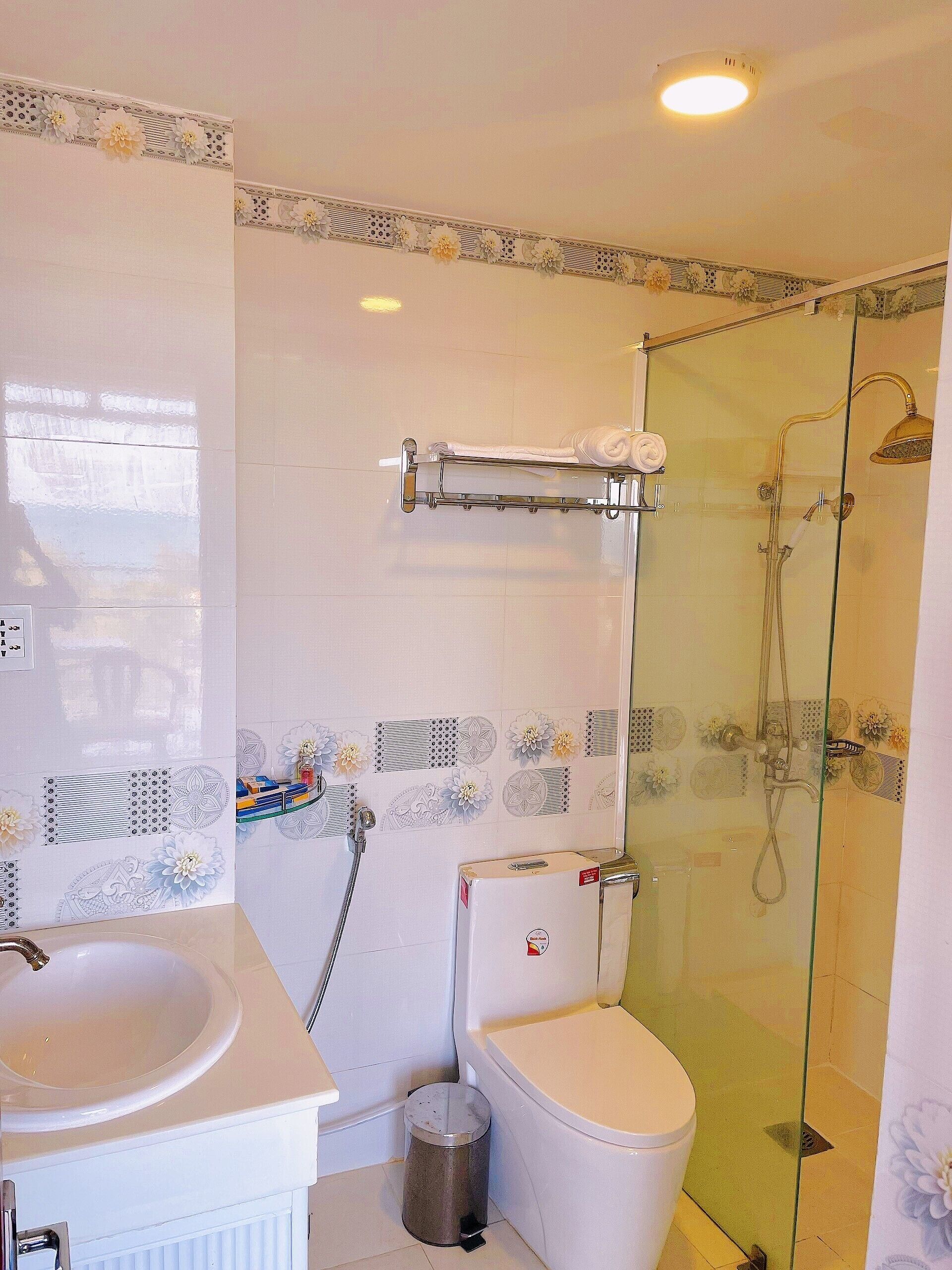 Un baño con ducha de mampara de vidrio, un inodoro y un lavamanos.