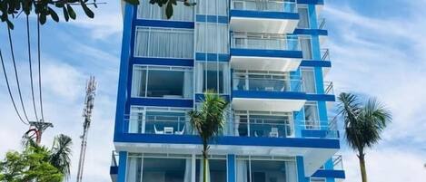 A multi-story hotel with a blue and white facade, named SUNRISE HOTEL.