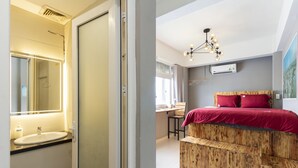 Un dormitorio con cabecera de madera, colcha roja y lámpara de araña moderna.