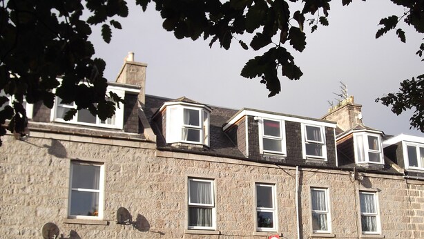 A stone building with multiple windows and a red door, labeled as a guest house. - Jasmine Central Guest House (Aberdeen)