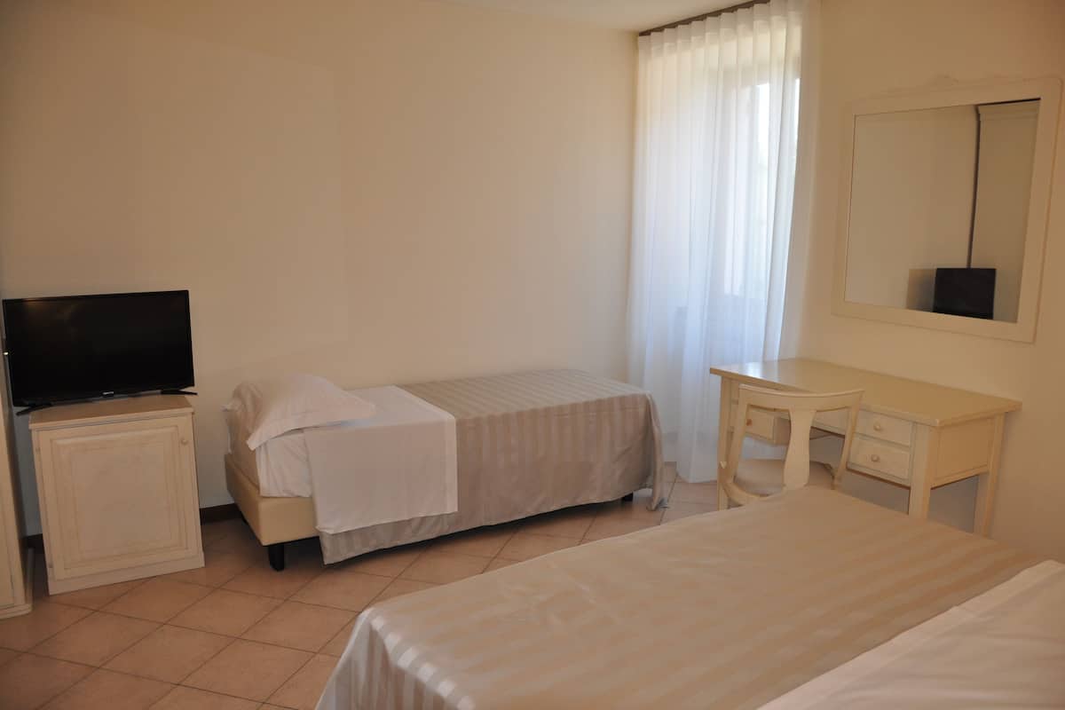 A hotel room with two beds, a television, a desk, and a mirror.
