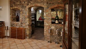 Una bodega con arcos de piedra, estanterías para vino y copas de vino.