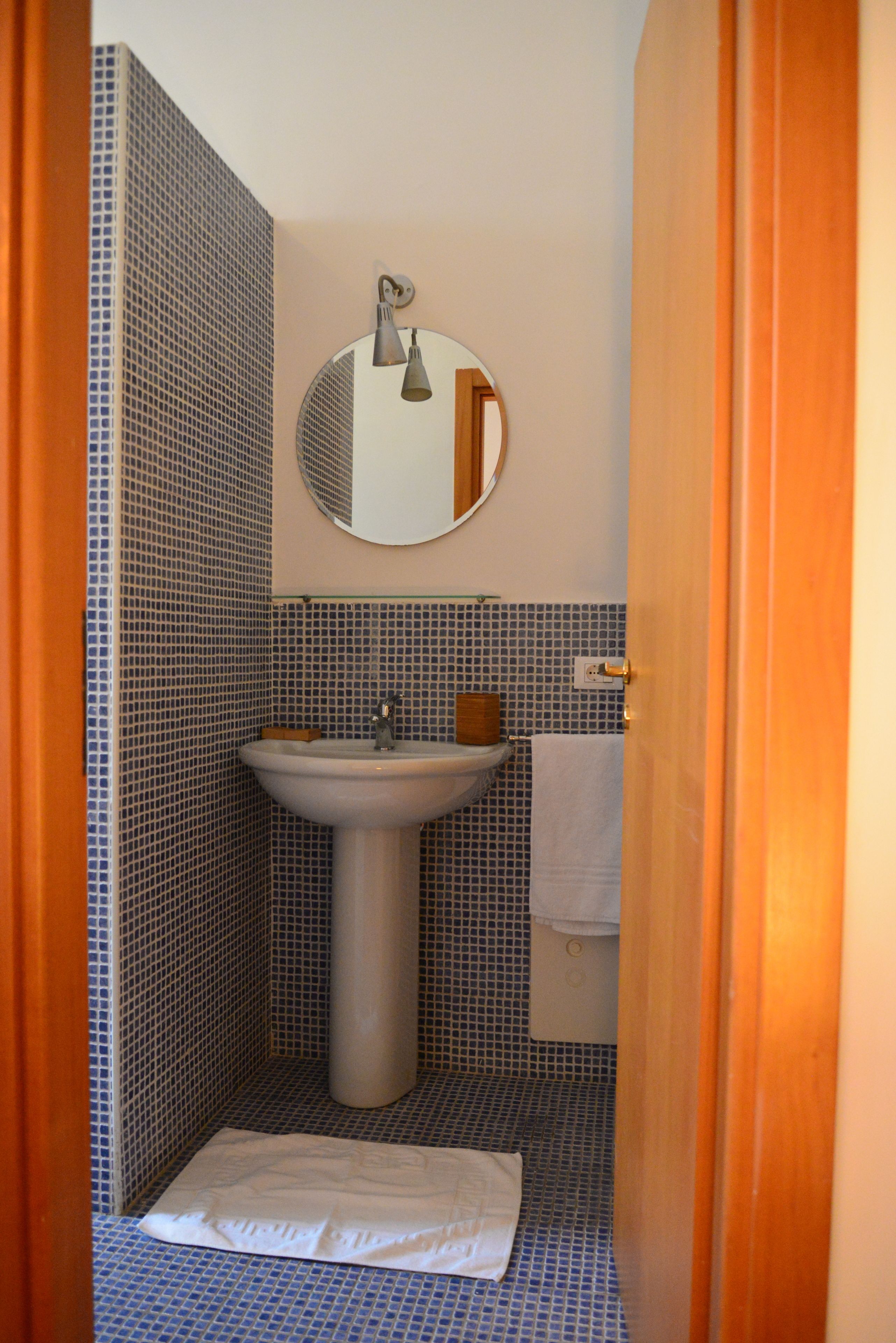 A bathroom with a sink, mirror, and tiled walls.
