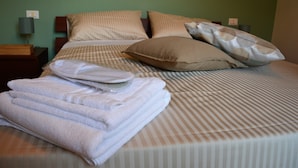 A neatly made bed with striped bedding, a pillow, and folded towels. - Dimora Paternò (Caserta)
