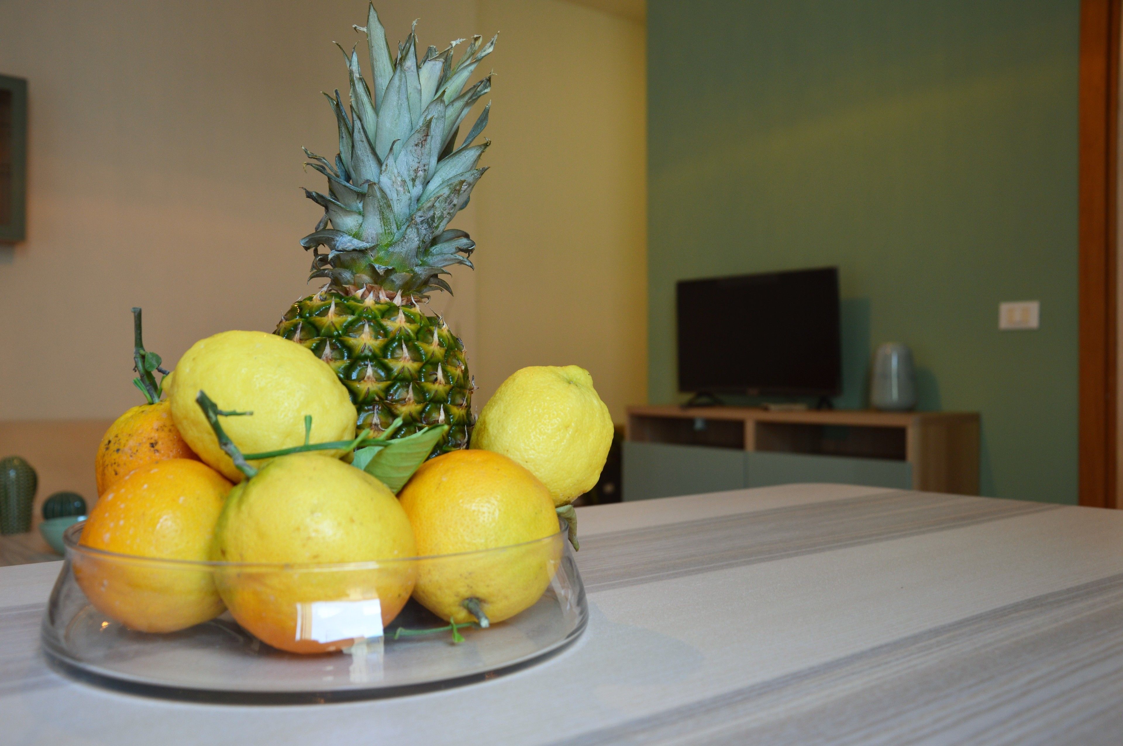 Eine Obstschale mit einer Ananas und Zitronen auf einem Tisch.
