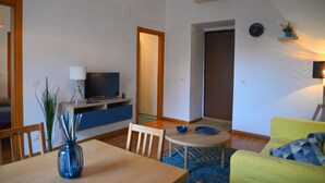 A modern living room with a dining area, a television, and a small table with a bowl. - Dimora Paternò (Caserta)
