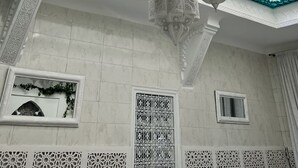 Un interior tradicional con diseños blancos y turquesa ornamentales, faroles colgantes y celosías de ventana intrincadas.